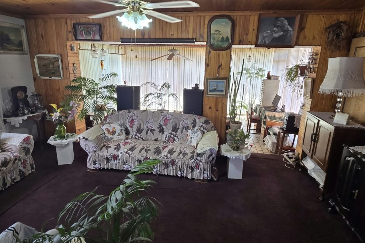 Spacious living area featuring traditional timber wall paneling and ceiling, with large sliding glass doors providing natural light and access to the adjacent space.