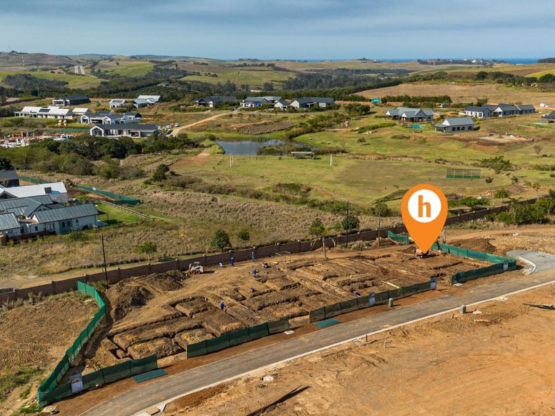 Aerial view of a residential construction site showing excavated foundations and perimeter walling within a developing estate.