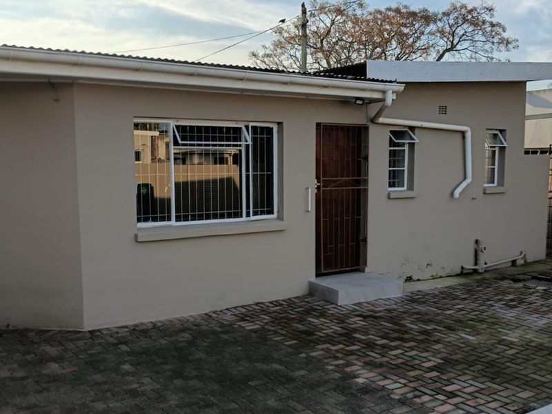 Front exterior view of a cottage featuring a paved driveway, security gate, and security bars on the windows.