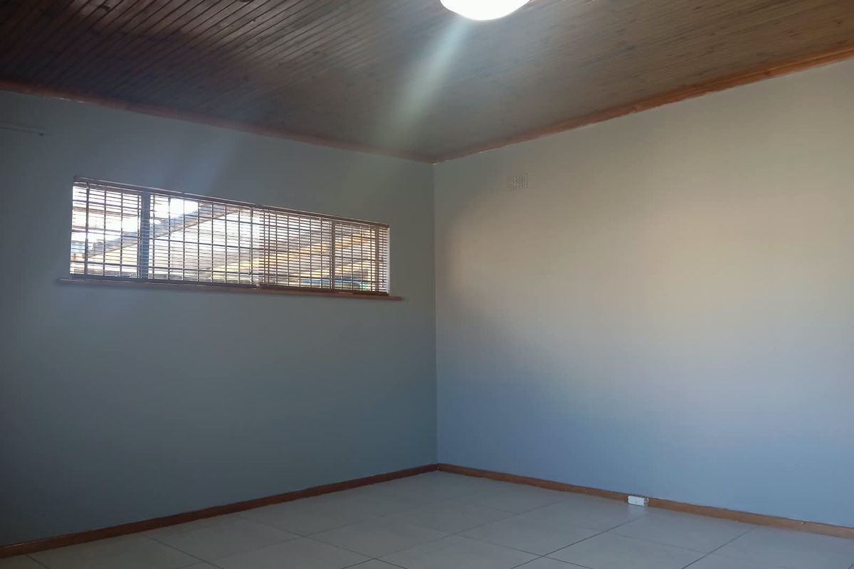 A spacious, empty bedroom featuring tiled flooring and a classic timber tongue and groove ceiling, providing a neutral canvas for personalization.