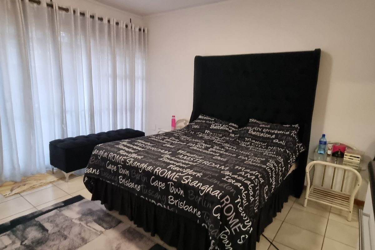 A bedroom featuring tiled flooring and a large sliding glass door providing access to the exterior.