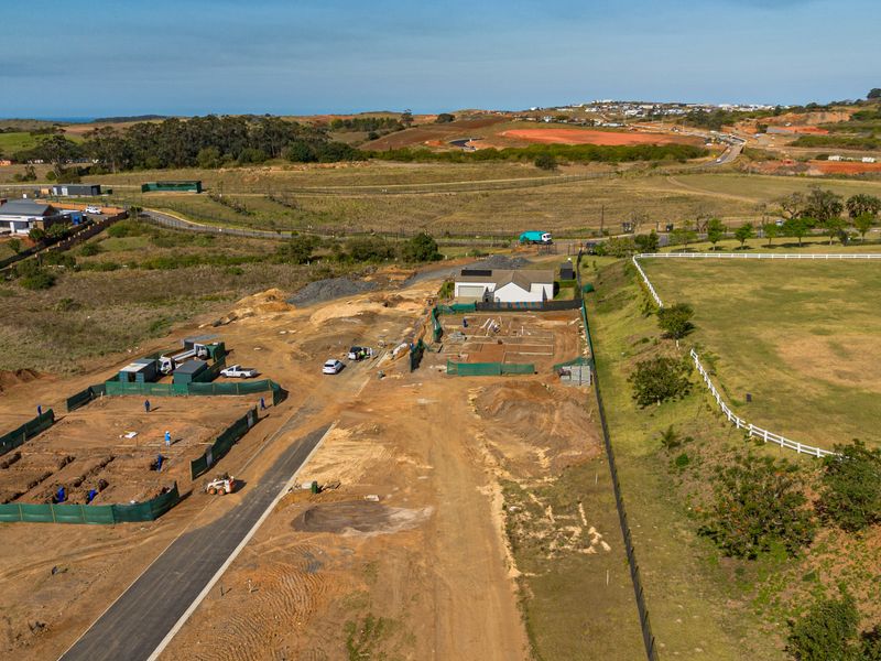 Aerial view of a residential development site showing ongoing construction, foundation work, and surrounding landscape in a rural estate setting.