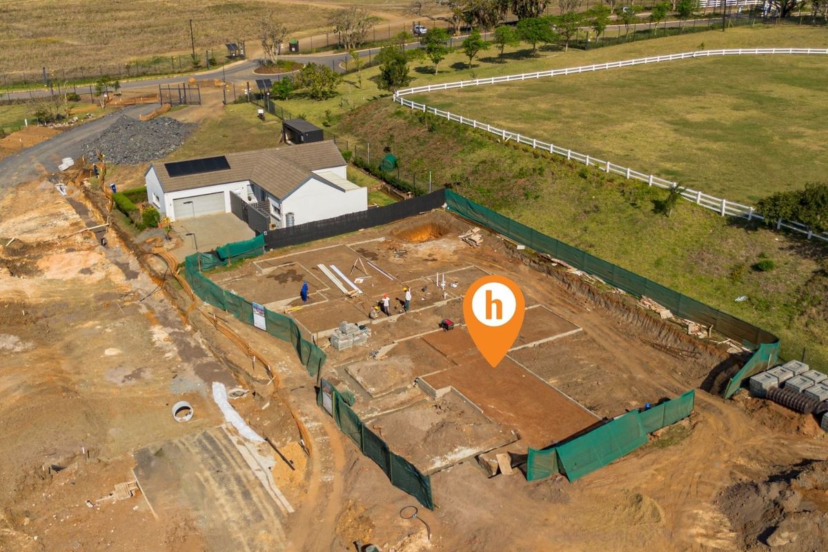 Aerial view of a residential construction site showing the concrete foundation slab and surrounding land development.