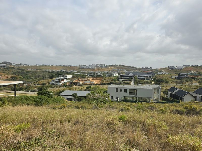 An elevated view overlooking a residential estate with surrounding natural landscape and neighboring modern homes.