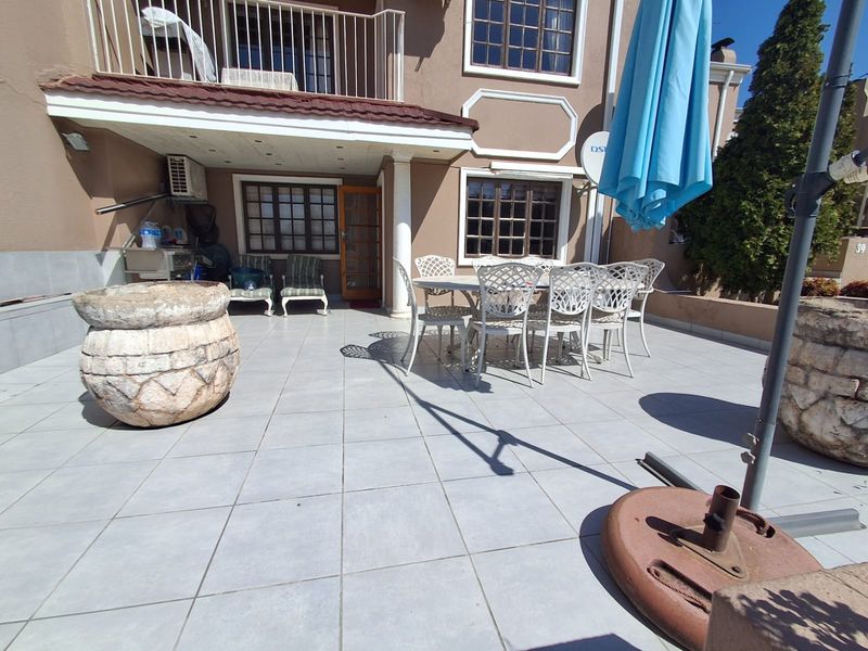 Spacious covered patio area with tiled flooring, providing an ideal outdoor space for entertaining and relaxation.
