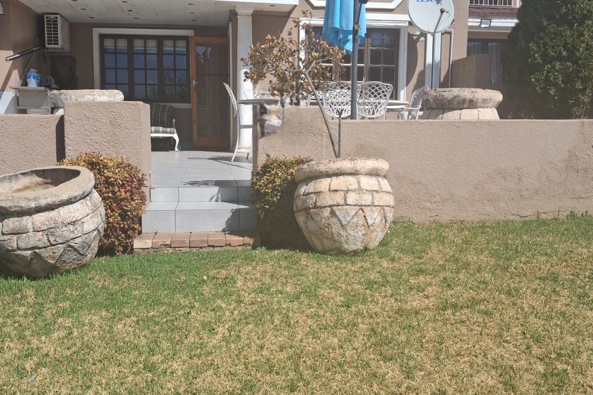 Rear view of the townhouse featuring a paved patio area, a balcony on the upper level, and a private garden space.