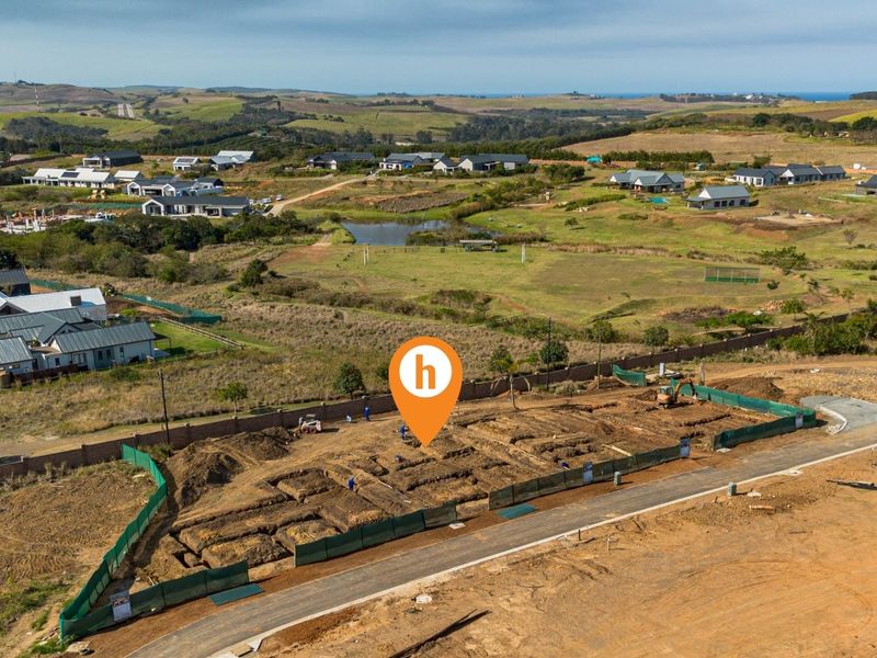 Aerial view of a residential construction site showing excavated foundation trenches and perimeter walling within a developing estate.