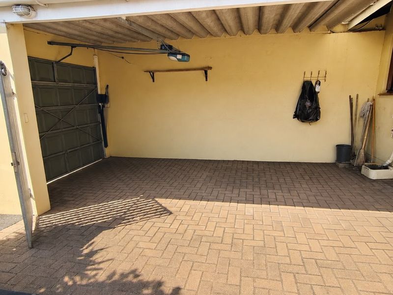 A functional single-car garage featuring paved flooring, a manual or automated garage door, and a corrugated roof structure.