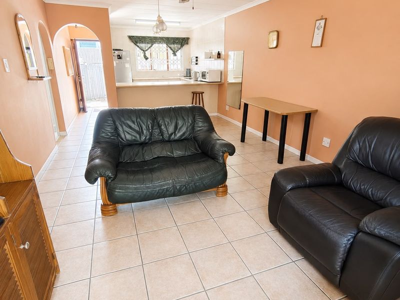 Open-plan living area featuring ceramic floor tiles, a ceiling fan, and an integrated breakfast bar connecting to the kitchen space.
