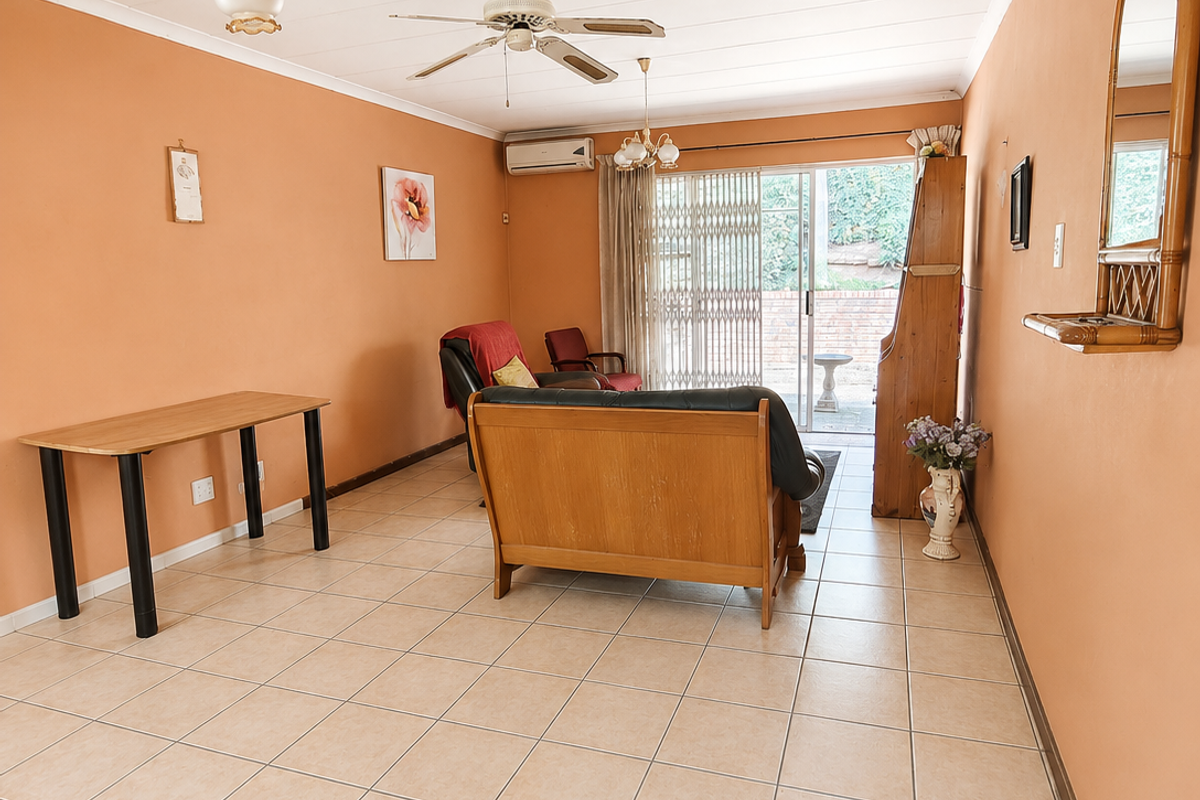 Spacious living room featuring neutral tiled flooring, a ceiling fan, split-system air conditioning, and sliding glass doors providing access to the outdoor area.