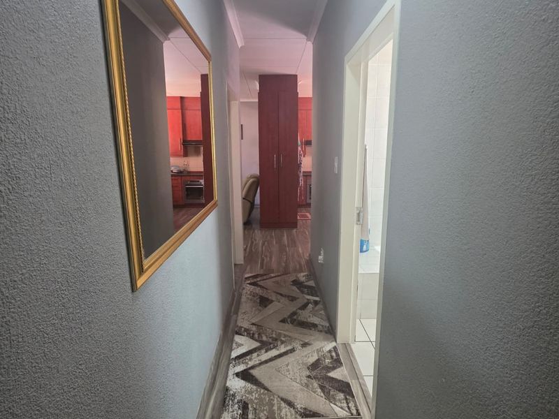 A well-maintained hallway featuring modern laminate flooring, coved ceilings, and recessed lighting, providing a clean transition between the home's living spaces.