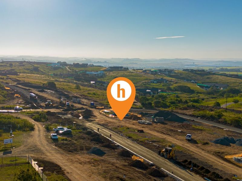 Aerial view of a residential development site showing ongoing road construction and cleared land plots in a rural landscape setting.