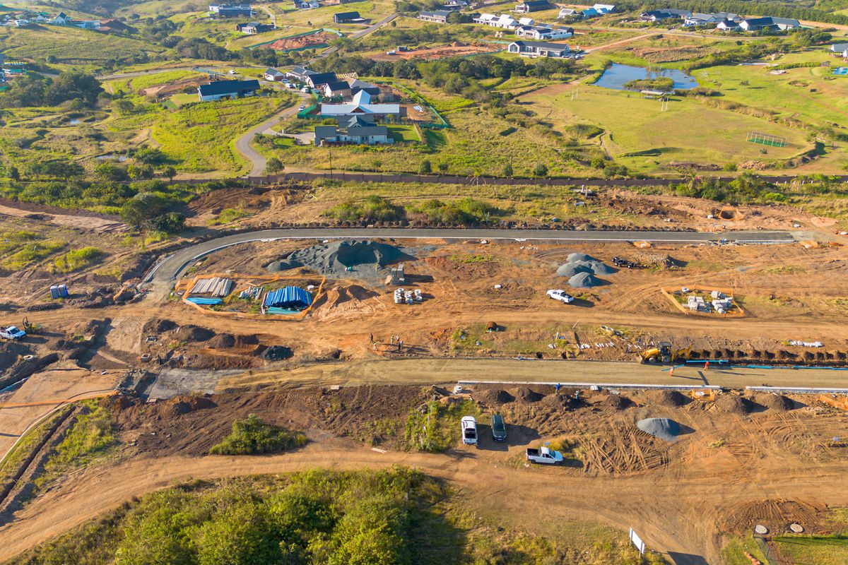 Aerial view of a residential development site showing ongoing road construction, utility installation, and cleared plots ready for building.