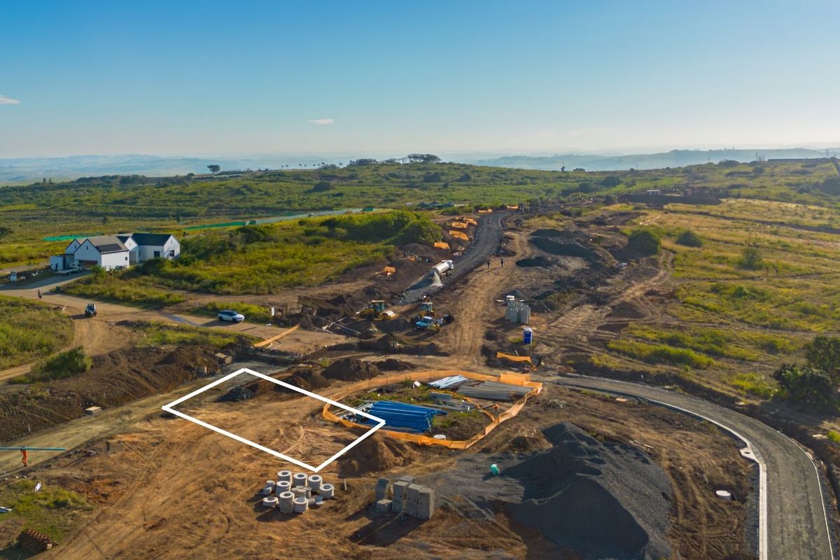 Aerial view of a residential development site showing cleared land, ongoing road construction, and surrounding landscape.