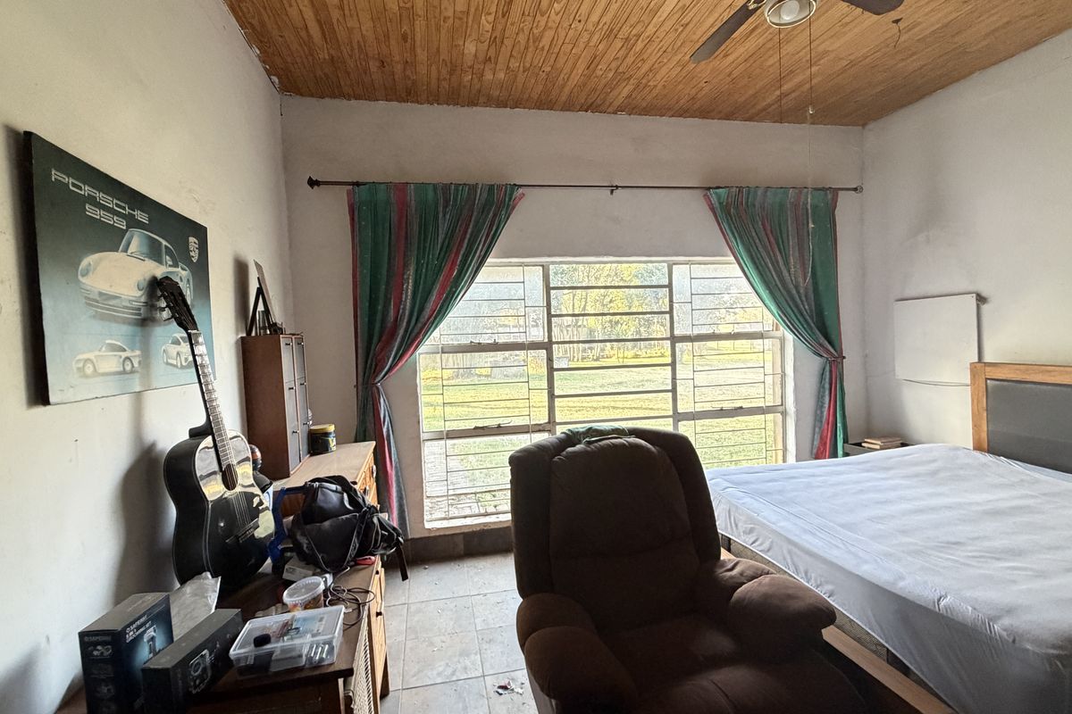 A bedroom featuring a timber ceiling, steel-framed windows, and tiled flooring, requiring cosmetic updates to improve its overall condition and appeal.
