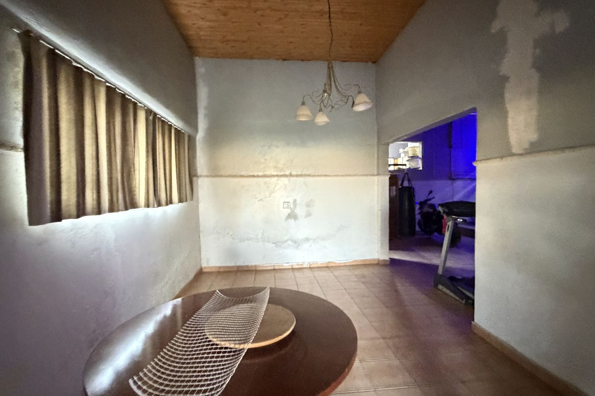 A living area featuring tiled flooring and a wooden ceiling, requiring cosmetic updates to the wall finishes to improve the overall aesthetic.