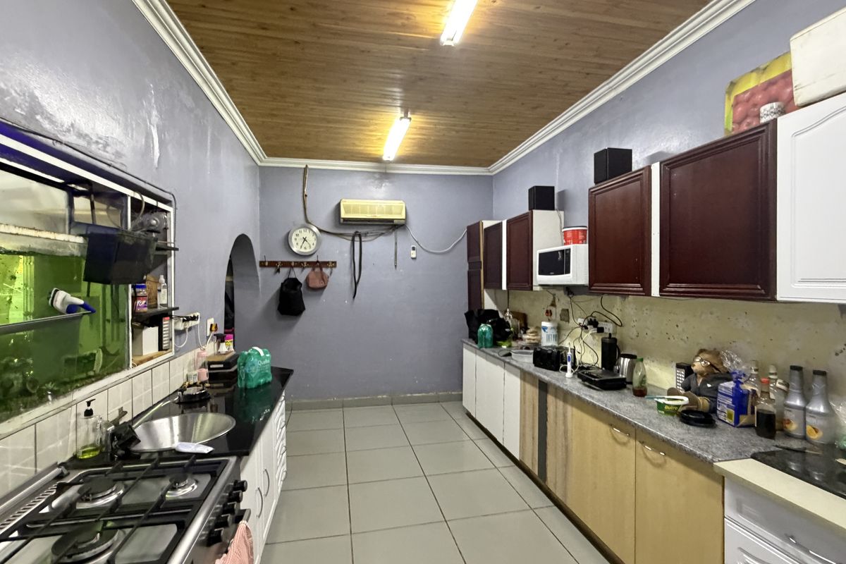 A functional kitchen featuring tiled flooring, timber ceiling, granite countertops, and built-in cabinetry, requiring cosmetic updates to the wall finishes.