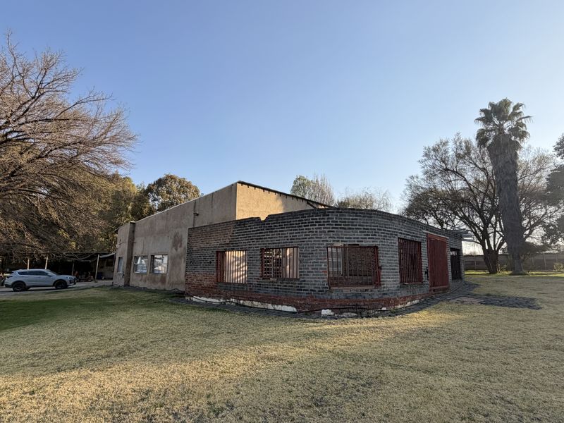 Rear view of a small holding property featuring a combination of plastered and exposed brick walls with security bars on the windows.