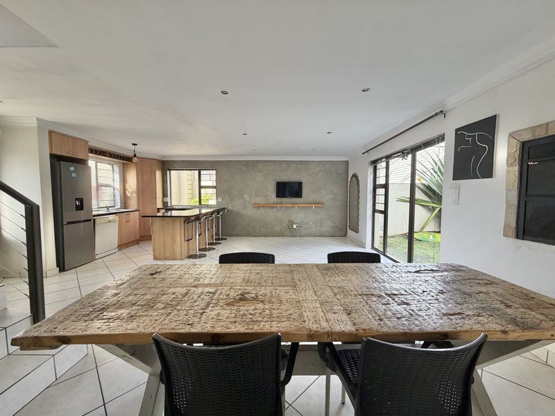 Spacious open-plan living and kitchen area featuring tiled floors, a central kitchen island, and large sliding doors providing access to the outdoor space.