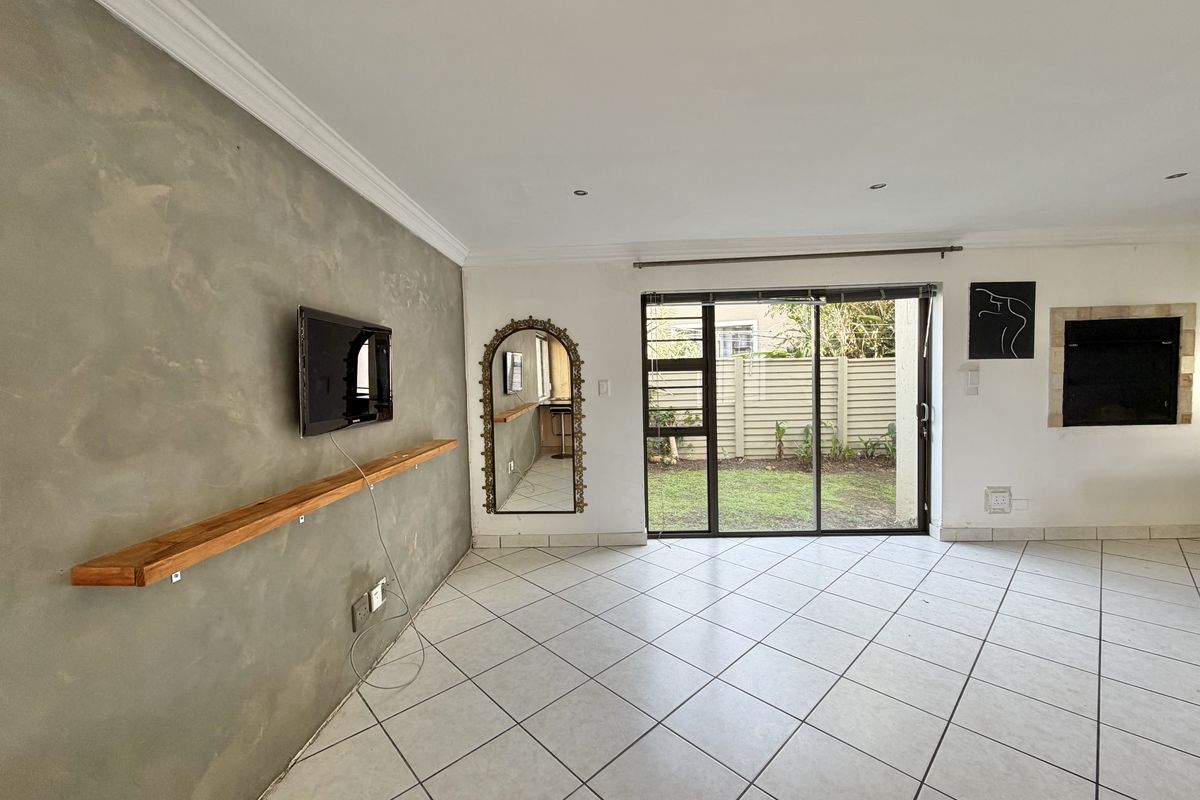 Spacious living area featuring tiled floors, a textured feature wall, built-in fireplace, and sliding glass doors providing direct access to the rear garden.