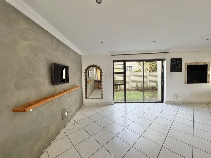 Spacious living area featuring tiled floors, a textured feature wall, built-in fireplace, and sliding glass doors providing direct access to the rear garden.