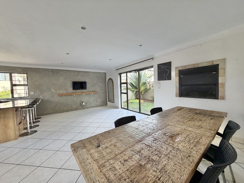 Spacious open-plan living and dining area featuring a built-in fireplace, cement feature wall, and sliding doors leading to the garden.