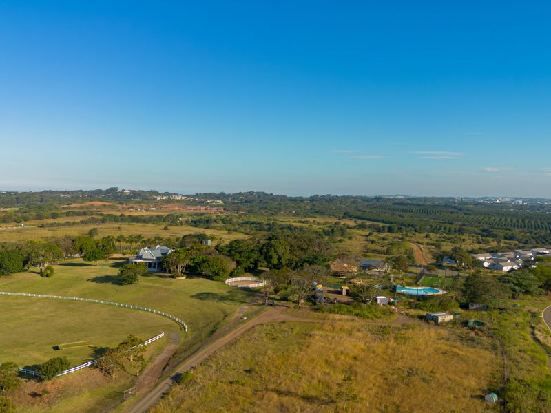 Aerial view of a large residential property featuring expansive grounds, a swimming pool, and established fencing within a rural landscape setting.
