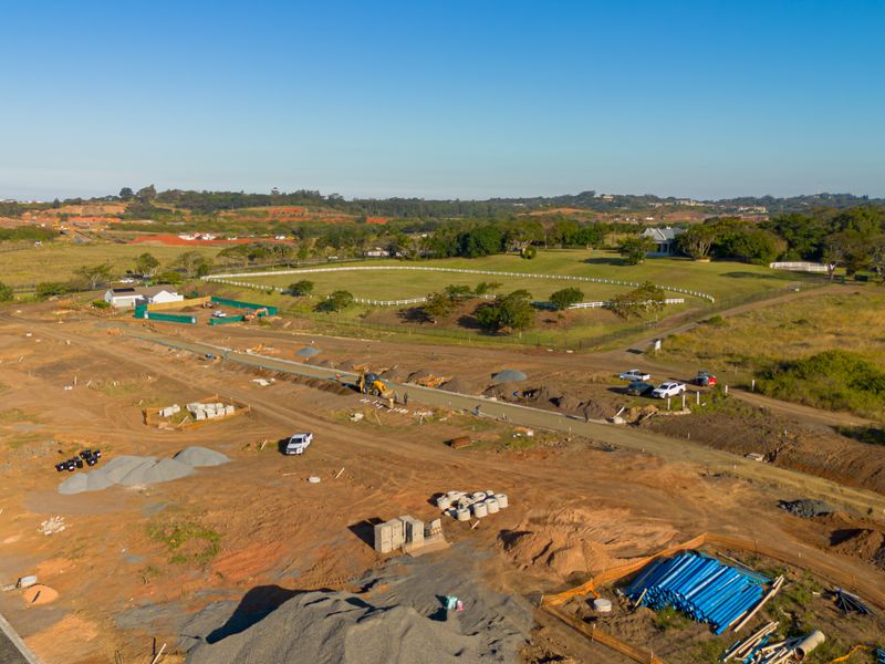 Aerial view of a residential development site showing ongoing infrastructure work, cleared land, and surrounding landscape.
