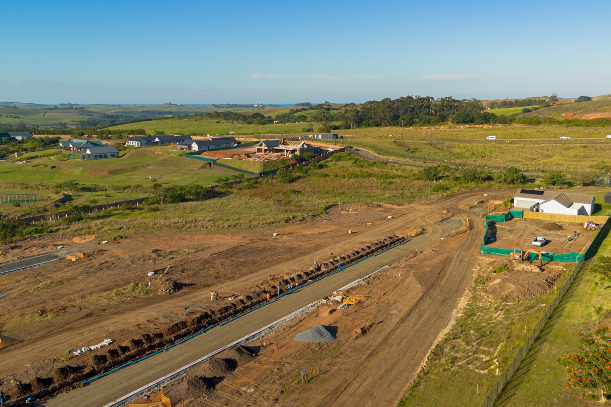 Aerial view of a residential development site showing ongoing road infrastructure construction, utility trenching, and surrounding estate landscape.