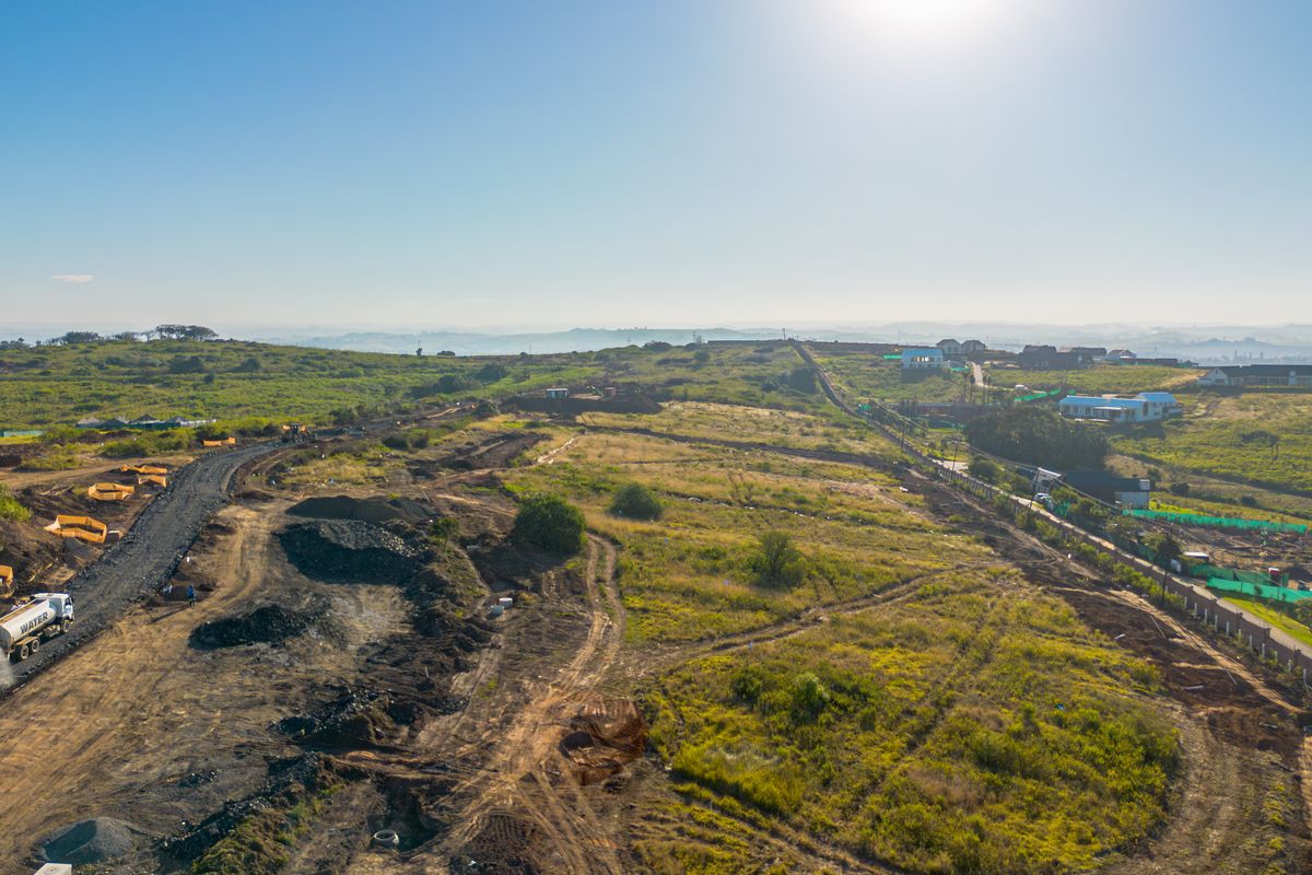 Aerial view of a large residential development site showing ongoing land preparation, earthworks, and access road construction.