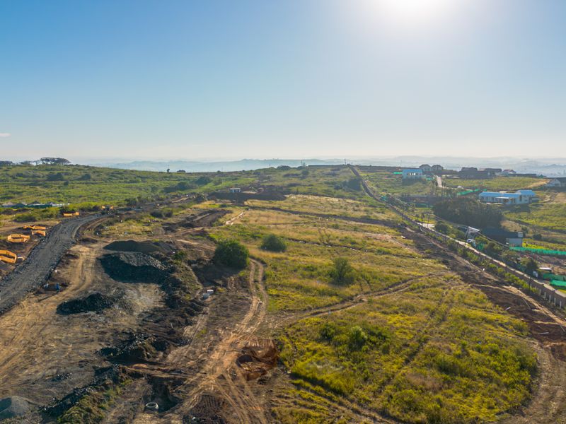 Aerial view of a large residential development site showing ongoing land preparation, earthworks, and access road construction.