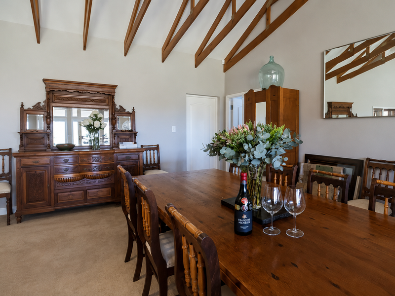 Spacious dining room featuring a high vaulted ceiling with exposed timber rafters and neutral wall finishes.