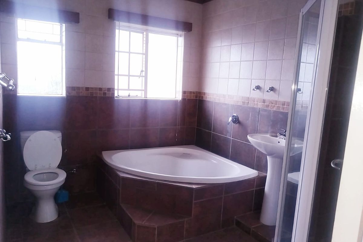 A functional bathroom featuring a corner bathtub, pedestal basin, separate shower enclosure, and tiled finishes throughout.