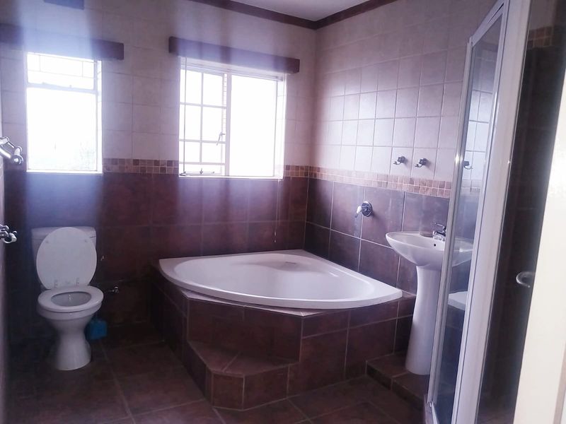 A functional bathroom featuring a corner bathtub, pedestal basin, separate shower enclosure, and tiled finishes throughout.