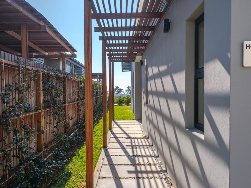 A well-maintained side passage featuring a timber pergola, paved walkway, and modern timber slat fencing with integrated climbing plants.