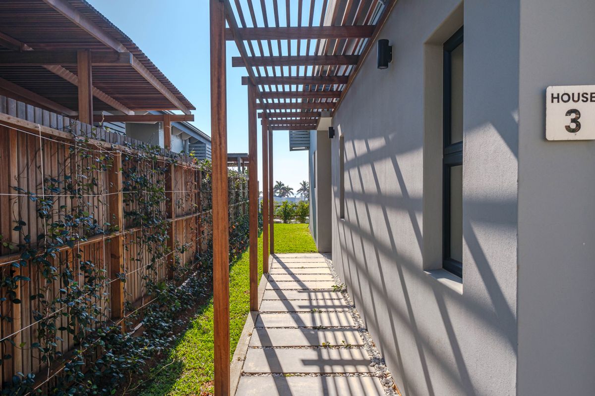 A well-maintained side passage featuring a timber pergola, paved walkway, and modern timber slat fencing with integrated climbing plants.