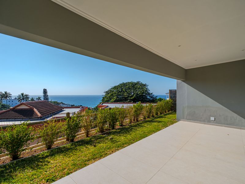 A spacious covered patio featuring tiled flooring and recessed lighting, offering an open-air feel with scenic coastal views.