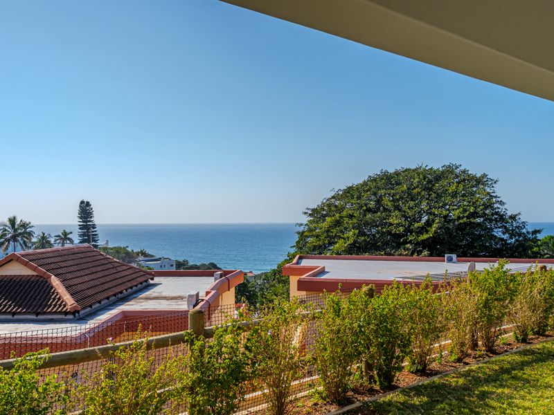 A scenic elevated view overlooking the ocean, featuring a well-maintained garden and surrounding coastal landscape.