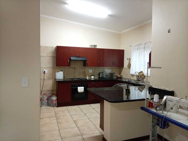 A functional kitchen featuring dark wood cabinetry, granite countertops, a built-in oven with hob, and tiled flooring, offering a practical layout for daily use.
