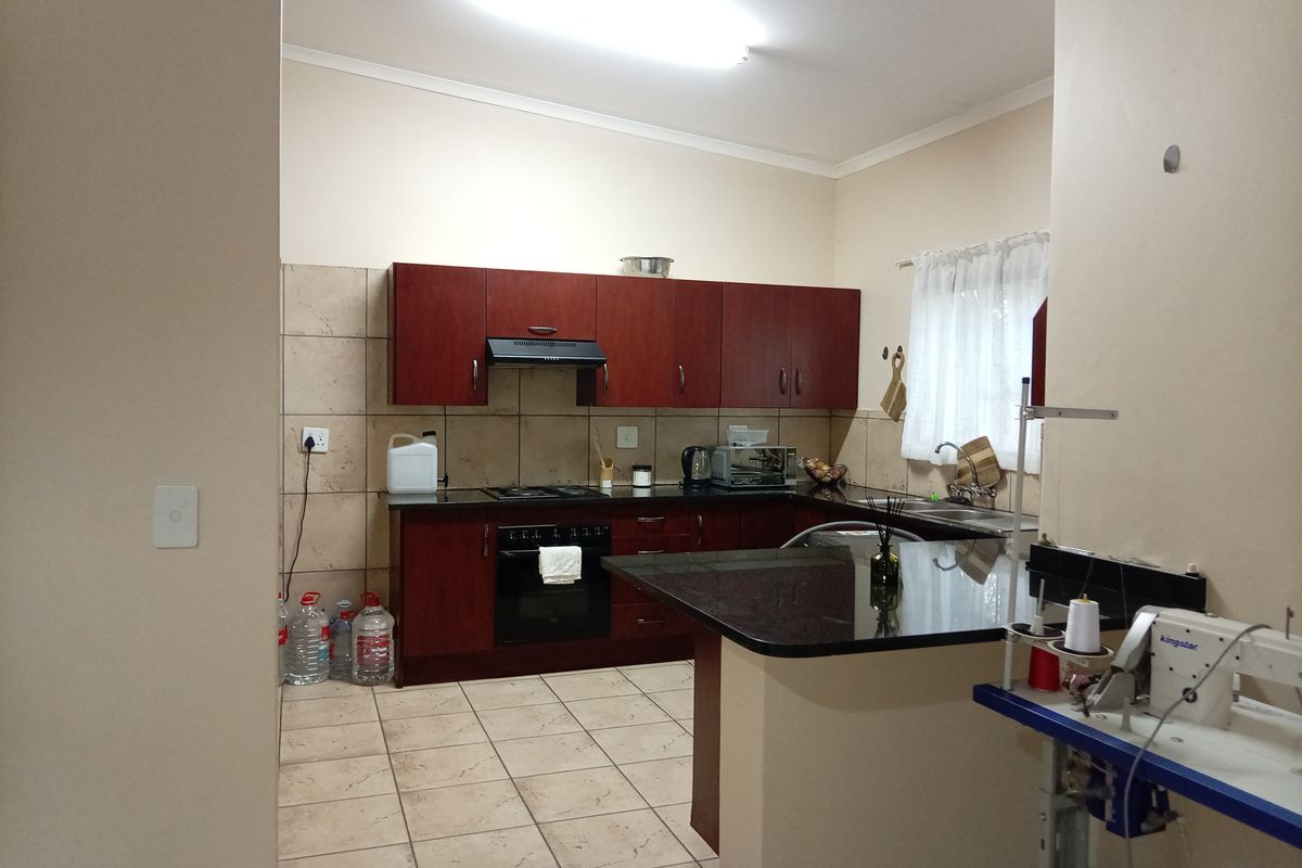 A functional kitchen featuring dark wood cabinetry, granite countertops, a built-in oven with hob, and tiled flooring, offering a practical layout for daily use.