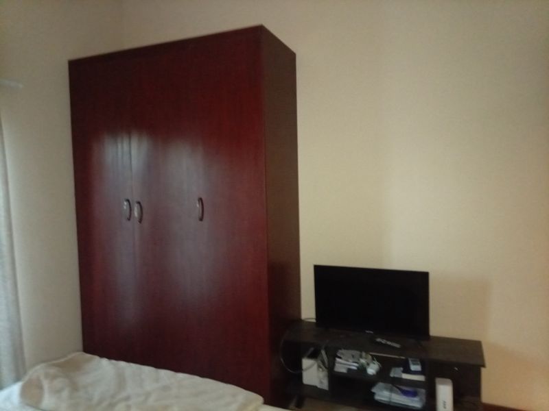 A bedroom featuring a dark wood built-in wardrobe, providing essential storage space within the room.