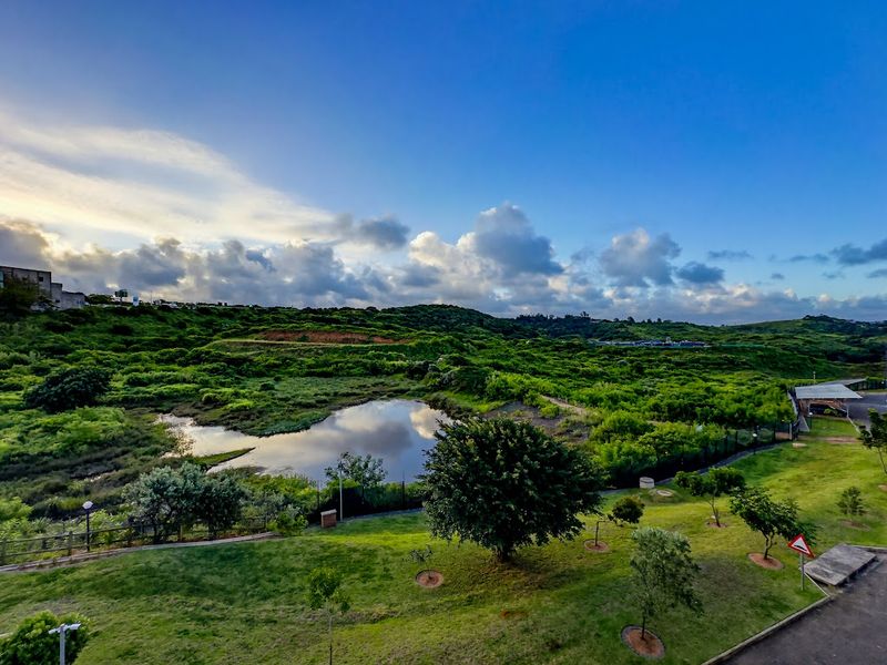 A scenic elevated view overlooking a natural pond and lush green landscape under a clear blue sky.