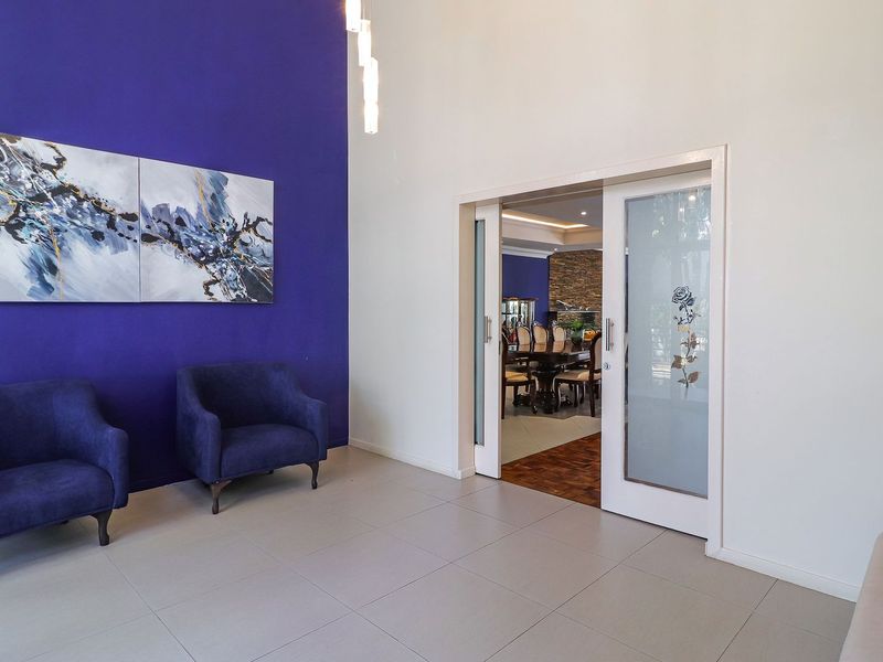 A bright entrance foyer featuring large format floor tiles, a bold accent wall, and sliding glass doors leading into the dining area.