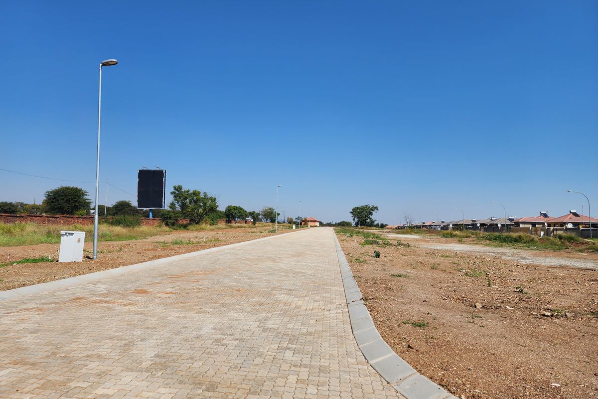 A view of a paved residential street with installed curbing, street lighting, and utility infrastructure in a developing residential area.
