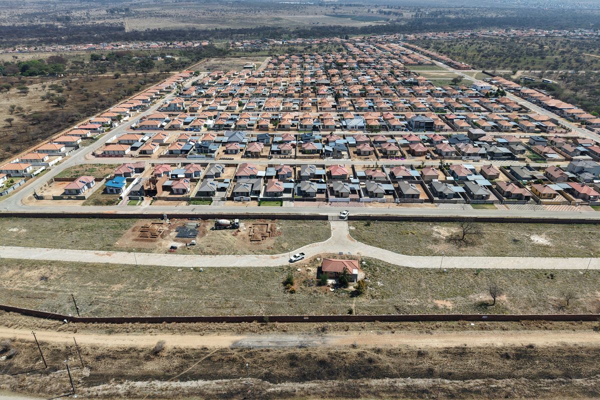 Aerial view of a residential development showing vacant land plots, paved access roads, and surrounding suburban housing infrastructure.