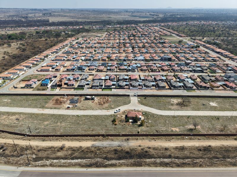 Aerial view of a residential development showing vacant land plots, paved access roads, and surrounding suburban housing infrastructure.