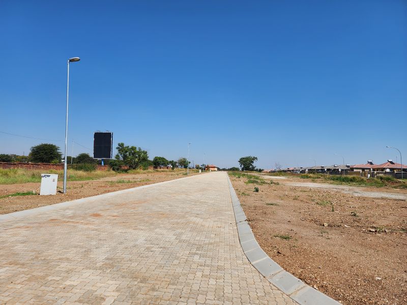 A view of a paved residential street with installed curbing, street lighting, and utility infrastructure in a developing residential area.