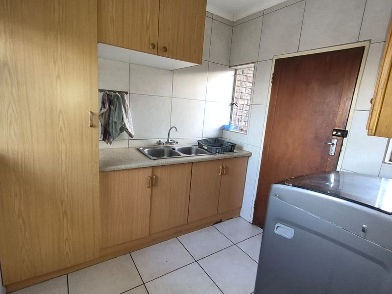 Functional laundry area featuring double basin sink, laminate cabinetry, and tiled splashback, providing practical utility space for household tasks.