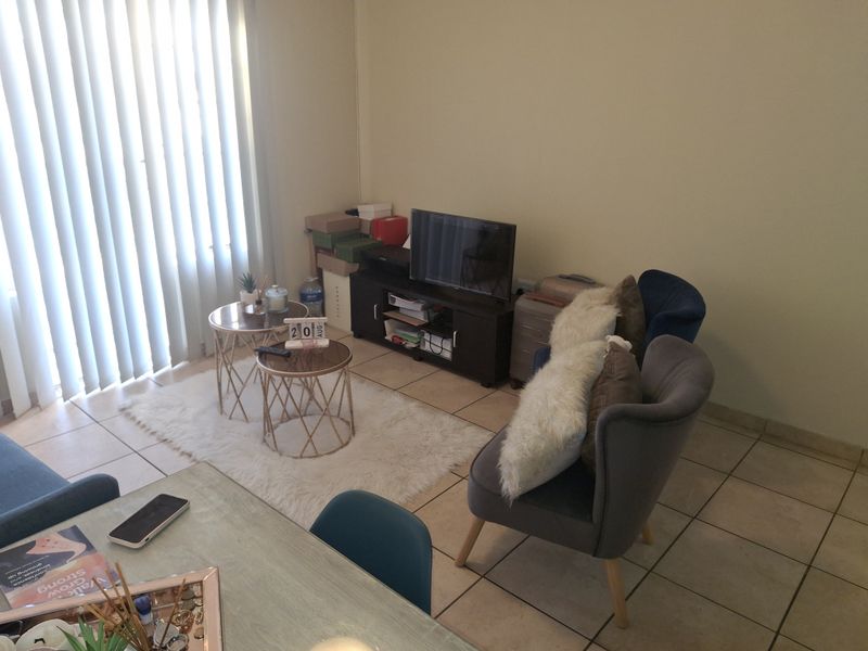 A living room area featuring tiled flooring and vertical blinds, providing a functional space with natural light.