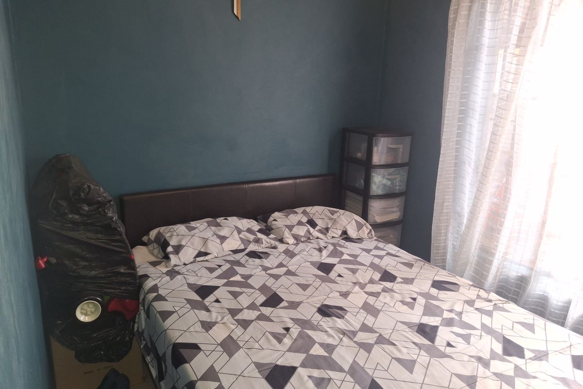 A bedroom featuring dark blue walls and a window with sheer curtains, providing a functional space for rest.